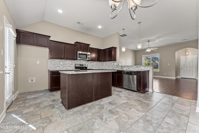 kitchen featuring ceiling fan with notable chandelier, stainless steel appliances, lofted ceiling, pendant lighting, and decorative backsplash