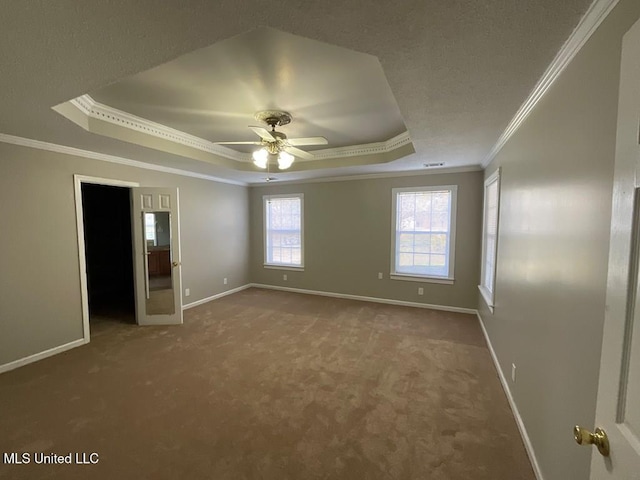 unfurnished bedroom with carpet flooring, a spacious closet, ceiling fan, a raised ceiling, and ornamental molding