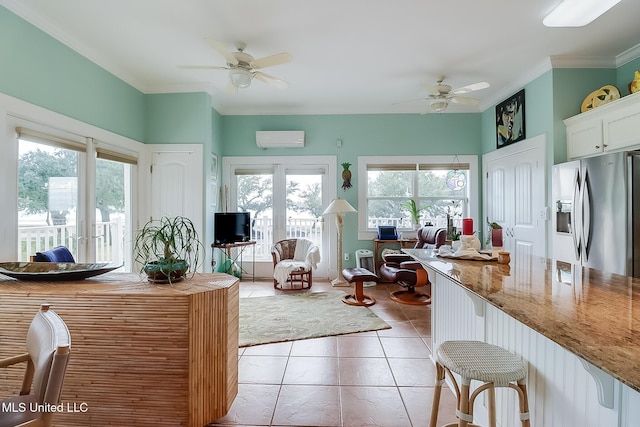 kitchen with light stone counters, a kitchen bar, ceiling fan, stainless steel fridge with ice dispenser, and a wall mounted air conditioner