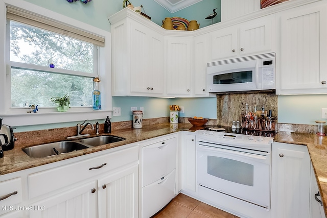 kitchen with white appliances, light tile patterned floors, sink, white cabinetry, and backsplash