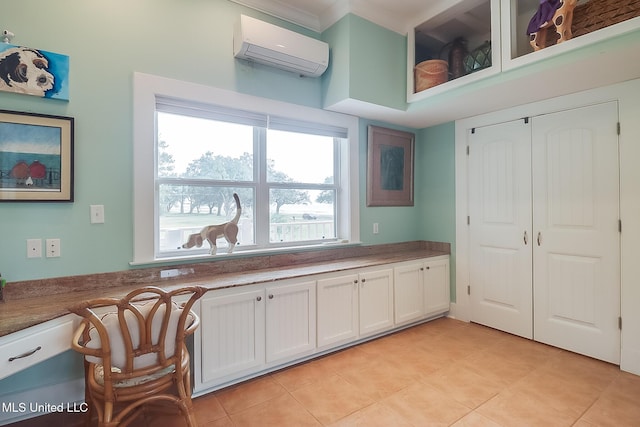 kitchen with light tile patterned flooring, white cabinetry, and a wall mounted AC