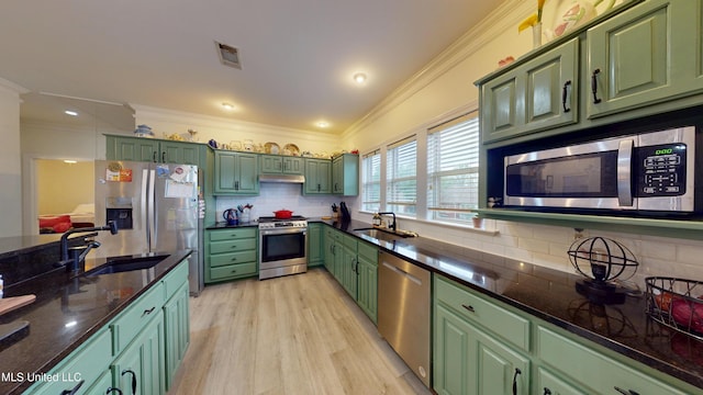 kitchen featuring a sink, stainless steel appliances, visible vents, ornamental molding, and green cabinets