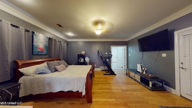 bedroom with baseboards, ornamental molding, light wood finished floors, and visible vents