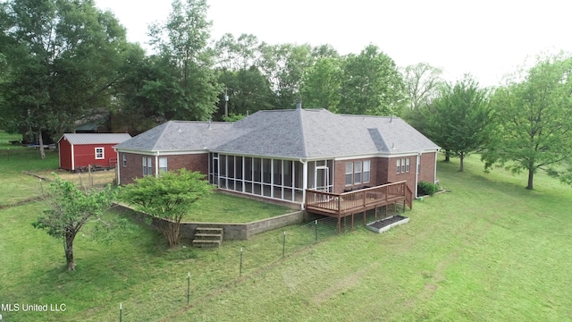 rear view of property featuring a lawn, a sunroom, and brick siding