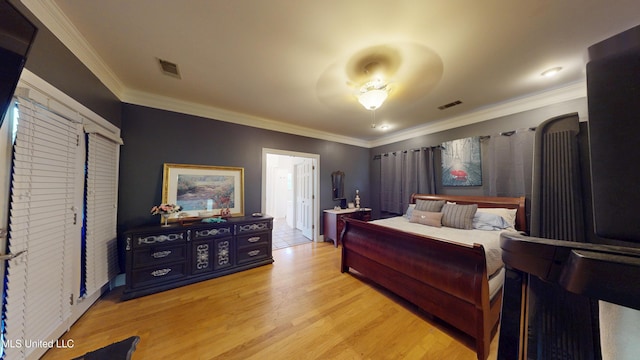 bedroom featuring baseboards, ornamental molding, light wood finished floors, and visible vents