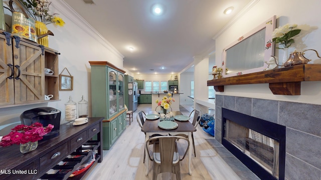 dining area with recessed lighting, ornamental molding, light wood finished floors, and a fireplace