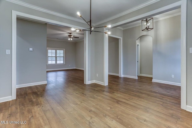 unfurnished room featuring arched walkways, crown molding, wood finished floors, baseboards, and ceiling fan with notable chandelier