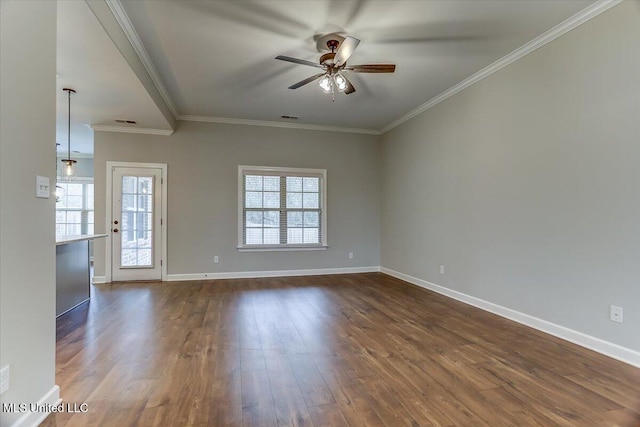 spare room featuring crown molding, plenty of natural light, dark wood finished floors, and baseboards