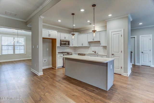 kitchen with stainless steel appliances, wood finished floors, a kitchen island, white cabinets, and tasteful backsplash