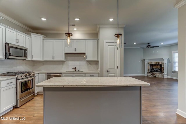 kitchen featuring a kitchen island, ornamental molding, stainless steel appliances, and a sink