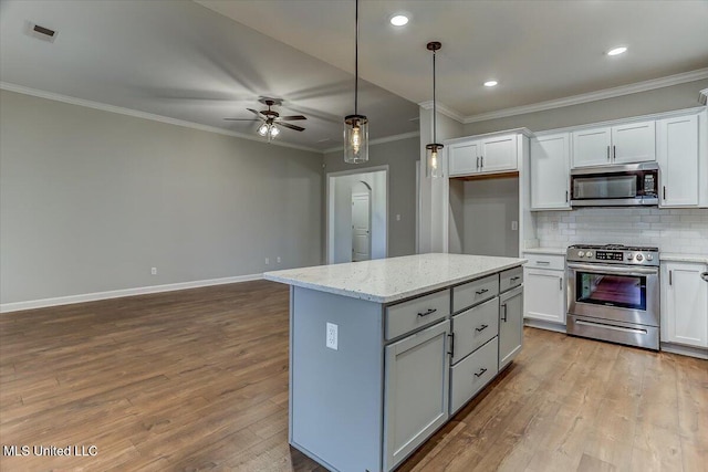 kitchen featuring ornamental molding, appliances with stainless steel finishes, wood finished floors, and tasteful backsplash