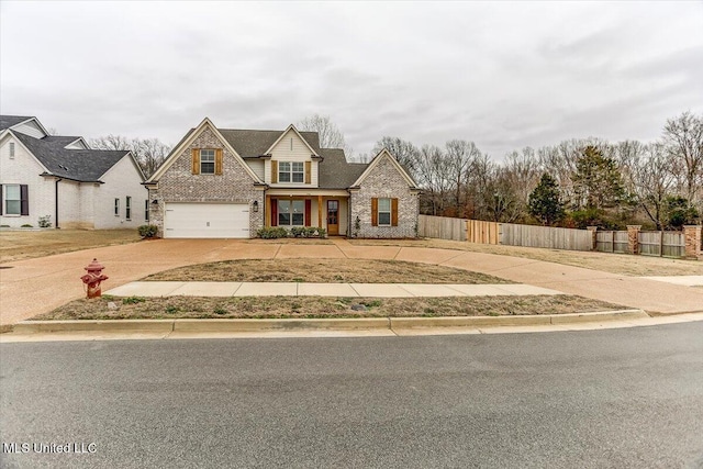 traditional-style home with a garage, fence, concrete driveway, and brick siding