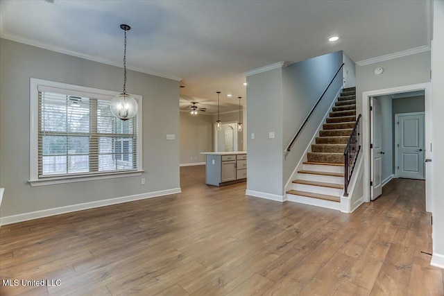 unfurnished living room featuring ornamental molding, stairway, wood finished floors, and baseboards