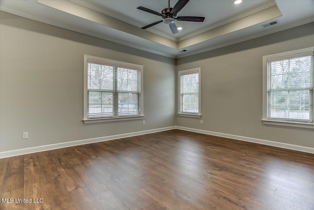 spare room featuring dark wood-style floors, ornamental molding, a raised ceiling, and visible vents