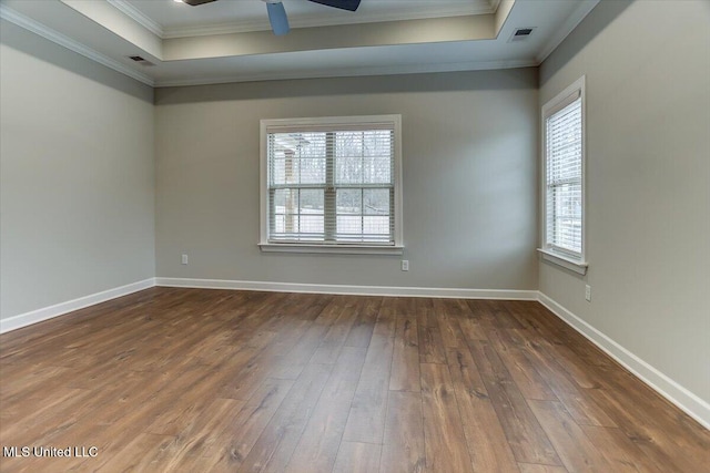 spare room with a tray ceiling, wood-type flooring, and crown molding