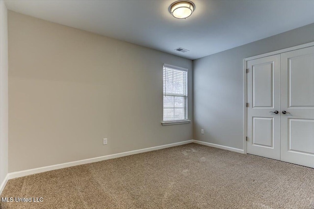 carpeted empty room featuring visible vents and baseboards