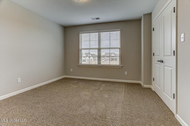 spare room with carpet, visible vents, and baseboards