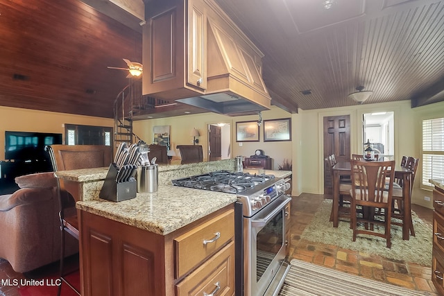 kitchen with ceiling fan, wooden ceiling, custom range hood, stainless steel range, and light stone counters