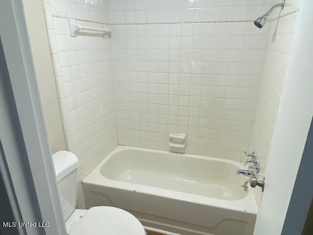 bathroom with toilet and tiled shower / bath