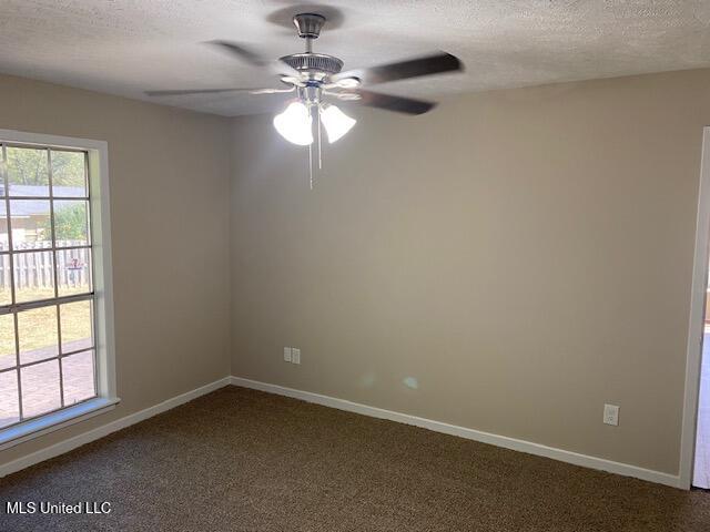 empty room with ceiling fan, a textured ceiling, and carpet floors