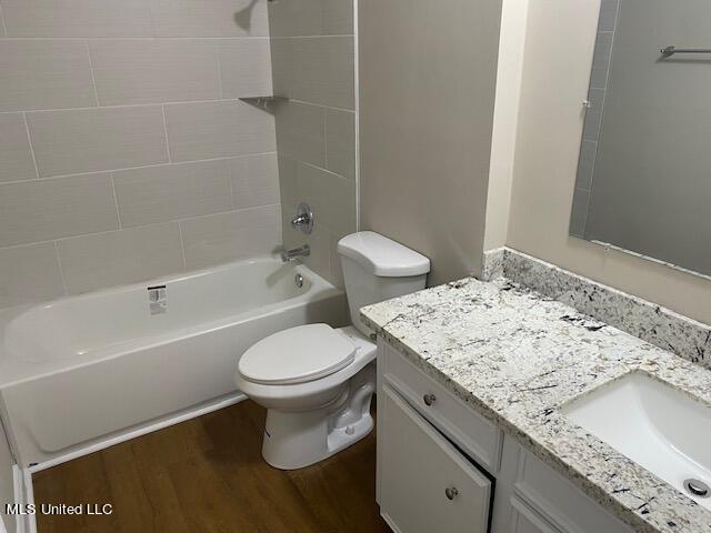 full bathroom featuring toilet, tiled shower / bath, vanity, and wood-type flooring