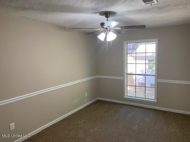 unfurnished room featuring ceiling fan, a textured ceiling, and dark colored carpet