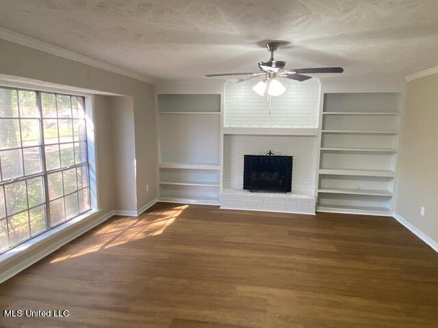 unfurnished living room with hardwood / wood-style floors, ceiling fan, a textured ceiling, a brick fireplace, and ornamental molding