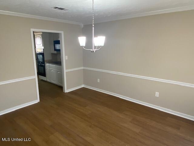 unfurnished dining area with crown molding, dark hardwood / wood-style floors, and an inviting chandelier