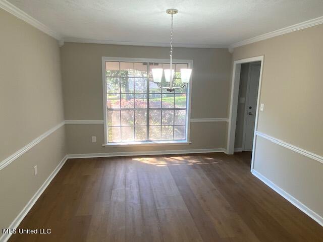 unfurnished dining area featuring a notable chandelier, ornamental molding, and dark hardwood / wood-style flooring