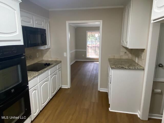 kitchen featuring white cabinets, backsplash, black appliances, dark wood-type flooring, and crown molding