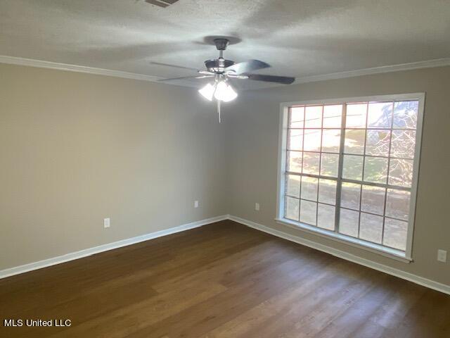 empty room featuring ornamental molding, dark hardwood / wood-style floors, and ceiling fan