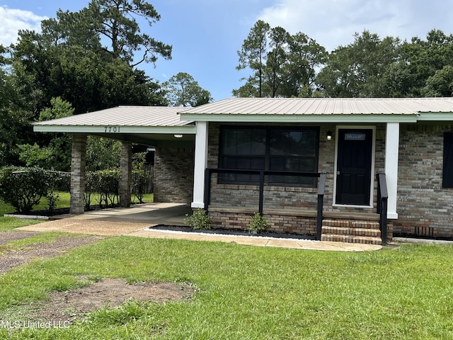 7701 Harold Ave, Moss Point, MS 39563 - view of front of house featuring a carport, a front yard, driveway, and a metal roof