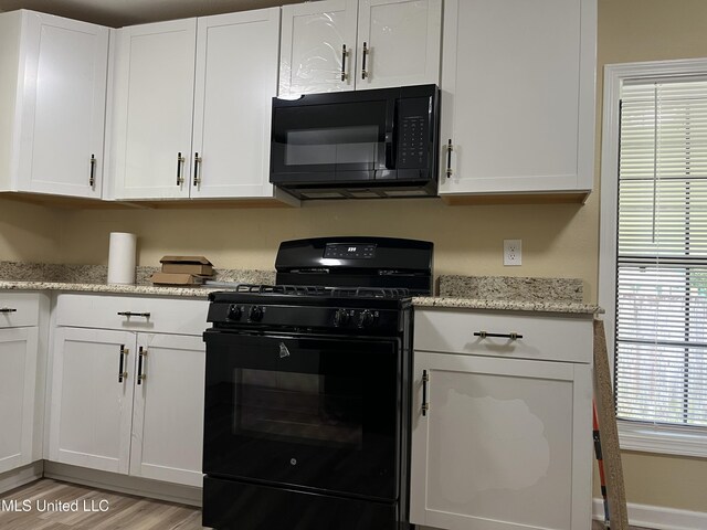 7701 Harold Ave, Moss Point, MS 39563 - kitchen featuring black appliances, light wood finished floors, white cabinets, and light stone counters