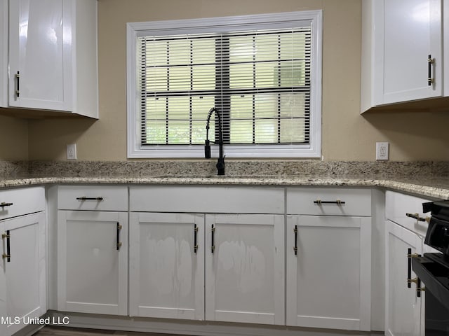 7701 Harold Ave, Moss Point, MS 39563 - kitchen with white cabinets, stove, and light stone counters