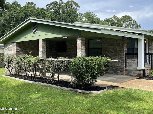 7701 Harold Ave, Moss Point, MS 39563 - view of front of home featuring a porch, brick siding, and a front lawn