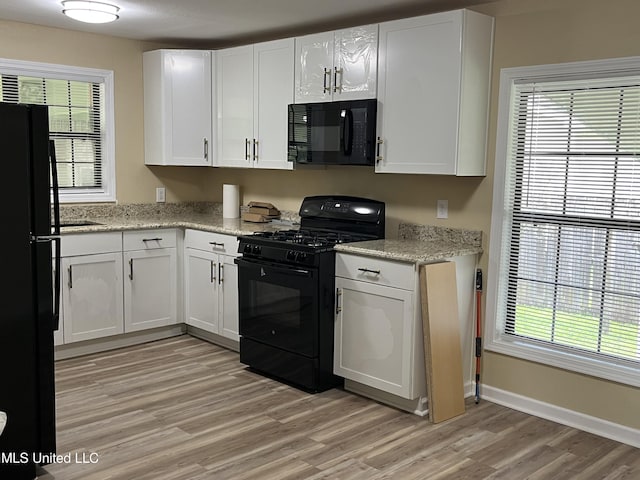 7701 Harold Ave, Moss Point, MS 39563 - kitchen featuring black appliances, light wood-style floors, white cabinets, and light stone counters
