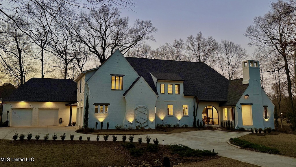 french country style house featuring driveway, a chimney, and a garage