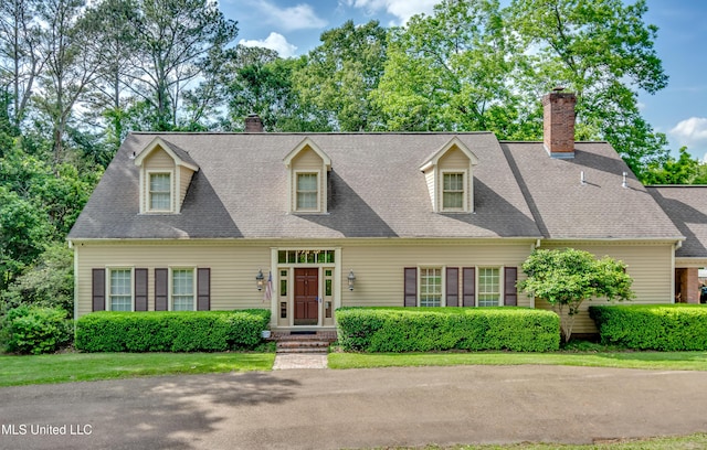 cape cod house with a shingled roof and a chimney