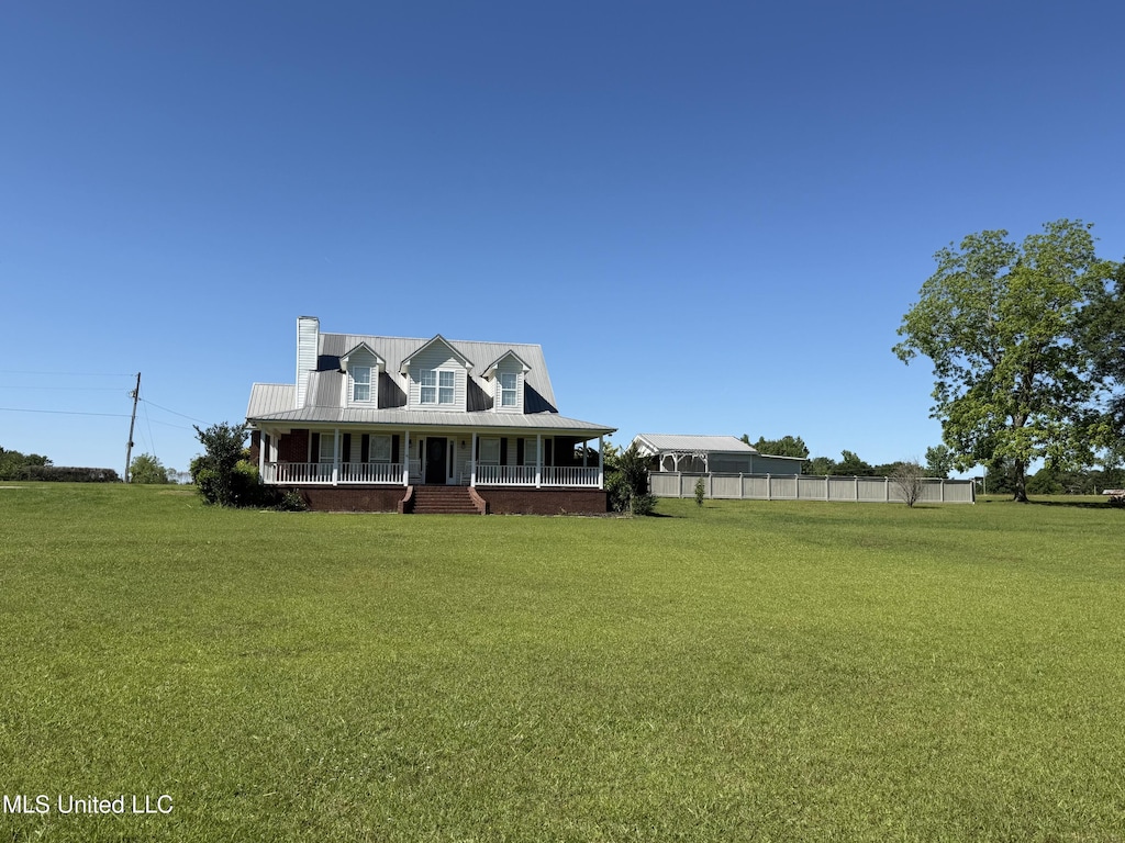 farmhouse inspired home with a front lawn, a porch, a chimney, and fence