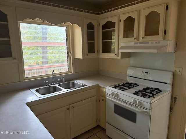 kitchen featuring white gas range, sink, and light tile patterned floors