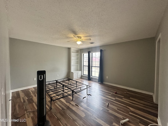 interior space with ceiling fan, dark wood-type flooring, built in features, and a textured ceiling