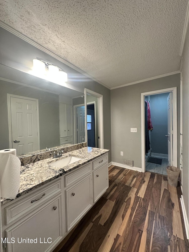 bathroom featuring ornamental molding, hardwood / wood-style floors, a textured ceiling, and vanity