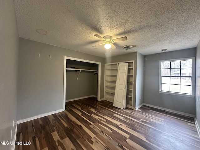 unfurnished bedroom with dark wood-type flooring, ceiling fan, and a textured ceiling