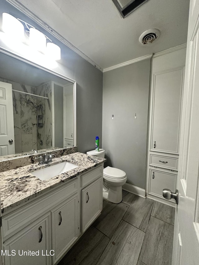 bathroom featuring toilet, a tile shower, ornamental molding, vanity, and hardwood / wood-style flooring