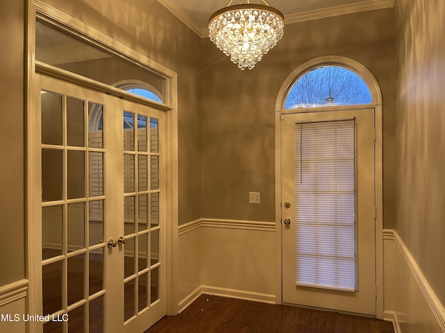 entryway with crown molding, french doors, dark hardwood / wood-style floors, and an inviting chandelier