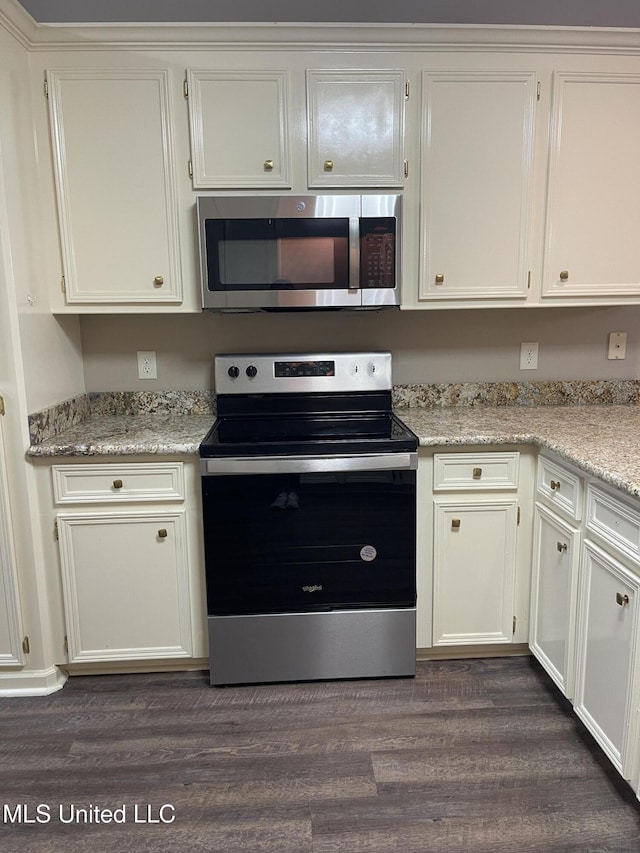 kitchen with stainless steel appliances, white cabinetry, and light stone counters