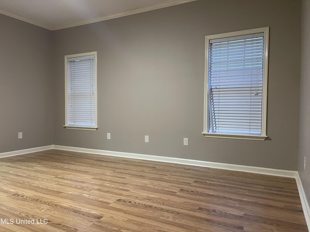 empty room featuring light wood-type flooring and crown molding