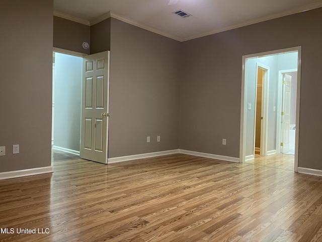 spare room featuring crown molding and light wood-type flooring