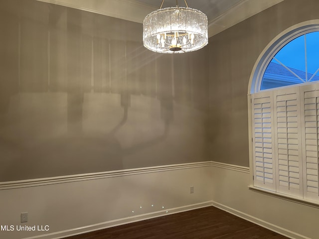 unfurnished room with dark hardwood / wood-style flooring, crown molding, and a notable chandelier