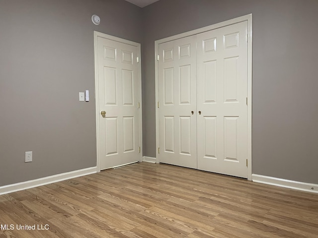 unfurnished bedroom with light wood-type flooring and a closet